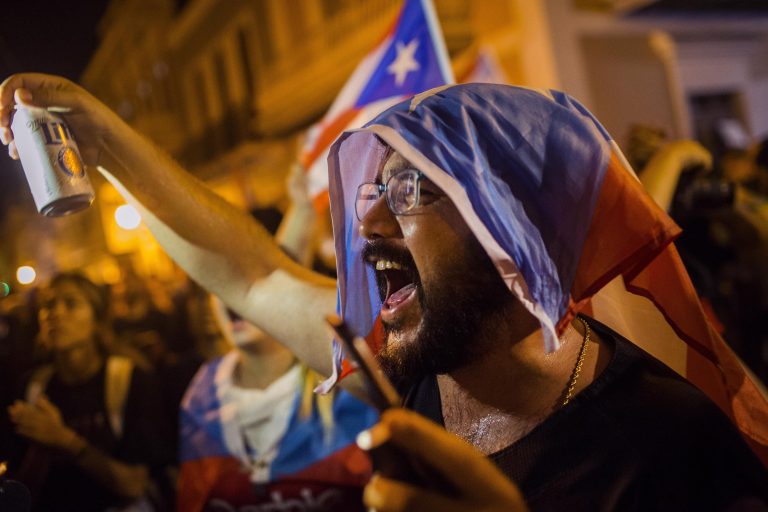 AP Photo,Un manifestante con una bandera puertorriqueña sobre la cabeza protesta en contra del gobernador de la isla, Ricardo Rosselló, el martes 23 de julio del 2019 en San Juan, Puerto Rico. (AP Foto/Dennis M. Rivera Pichardo)