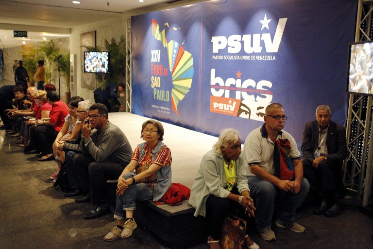AP Photo,Varios participantes permanecen sentados cerca de un carteles del Foro de Sao Paulo y del Partido Socialista Unido de Venezuela durante la primera jornada de esa reunión en Venezuela, el viernes 26 de julio de 2019. (AP Fhoto/Leonardo Fernandez)