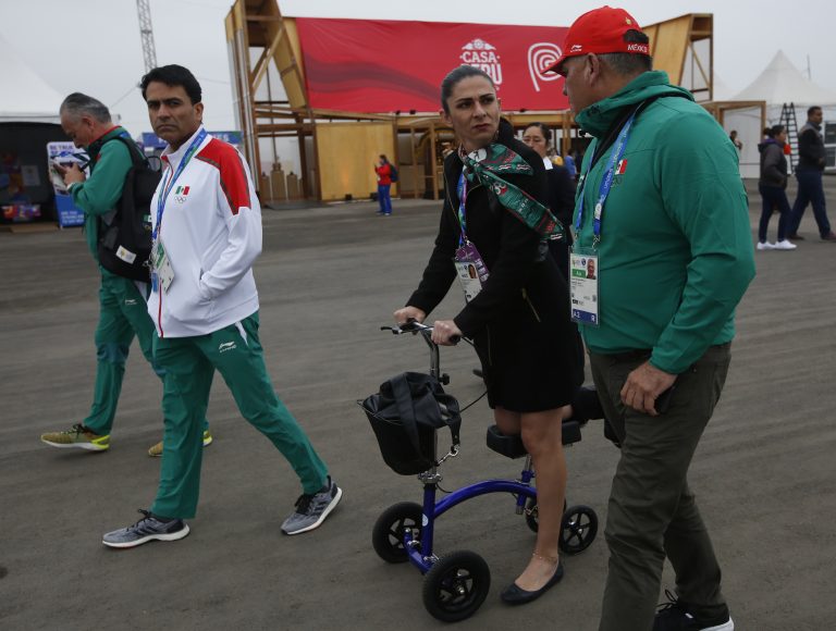AP Photo,Ana Guevara, exatleta y directora de la Comisión Nacional de Cultura Física y Deporte de México, llega con ayuda de una andadera ortopédica a la Villa Panamericana de Lima, el jueves 25 de julio de 2019 (AP Foto/Moisés Castillo)