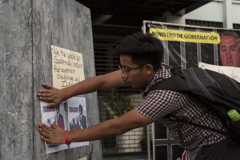 AP Photo,Un hombre coloca carteles que muestran una caricatura del presidente guatemalteco Jimmy Morales con la palabra 