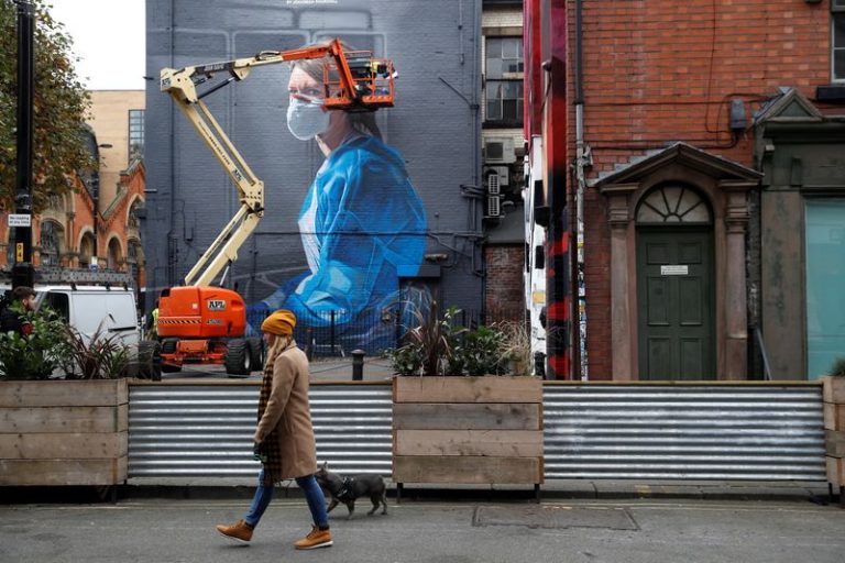 LYNXMPEG9S11X.jpg,FILE PHOTO: A woman walks past as an artist works on a mural during the outbreak of the coronavirus disease (COVID-19), in Manchester, Britain October 18, 2020. REUTERS/Phil Noble; Crédito: PHIL NOBLE, Reuters